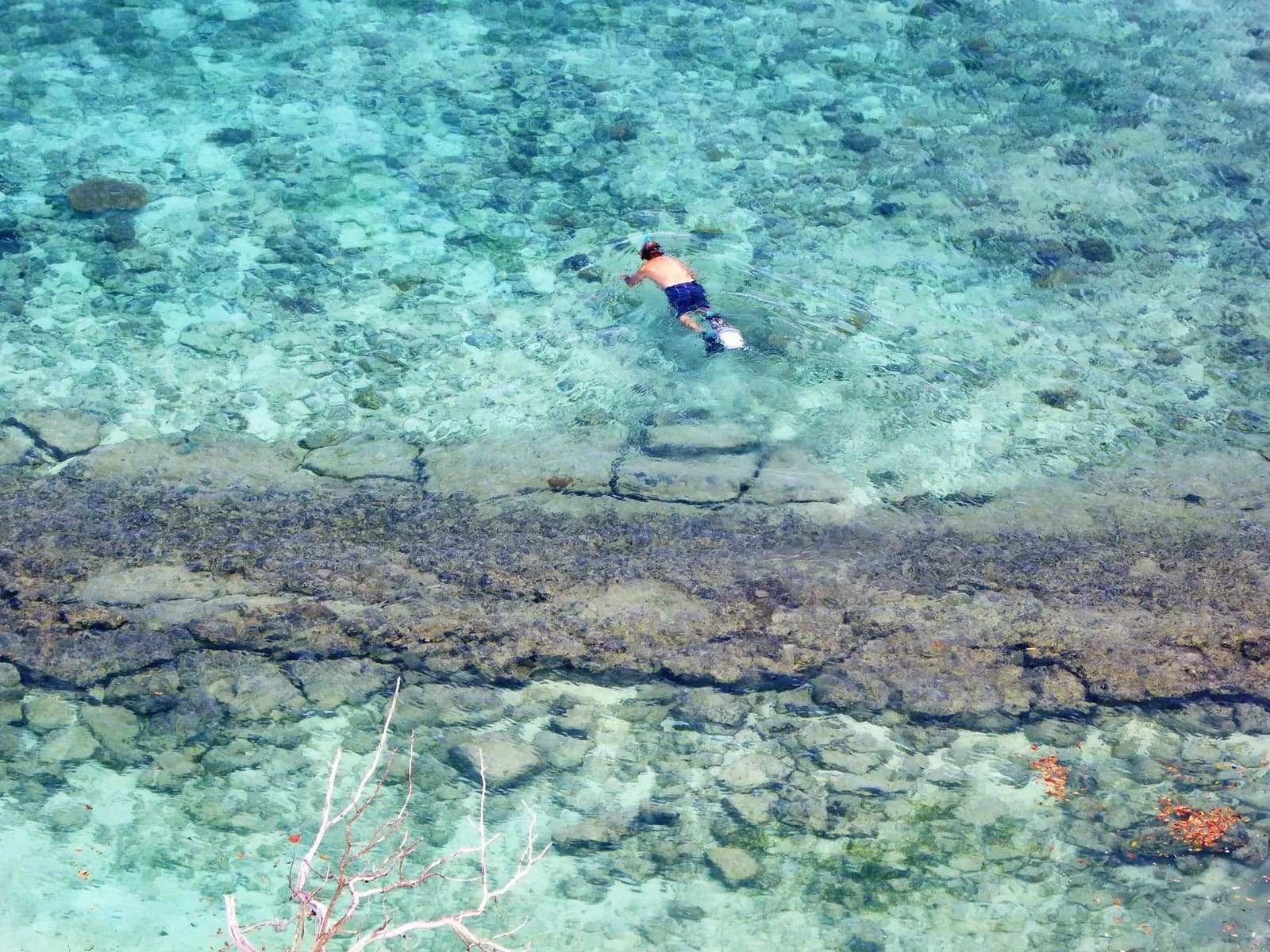 Vue aérienne d'un lagon turquoise ponctué de bancs de sable et de récifs, bordé par l'océan bleu profond