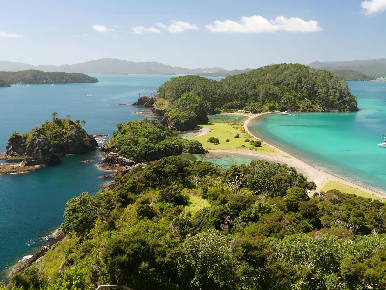 Baie aux eaux turquoise ponctuée d'îlots rocheux boisés, ambiance des baies du Pacifique