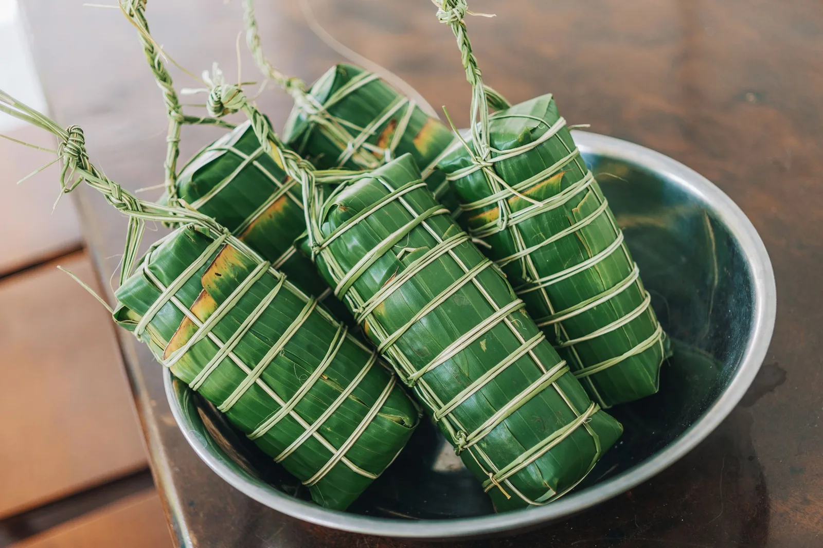Paquets de nourriture enveloppés dans des feuilles de bananier et ficelés, prêts pour la cuisson à l’étouffée