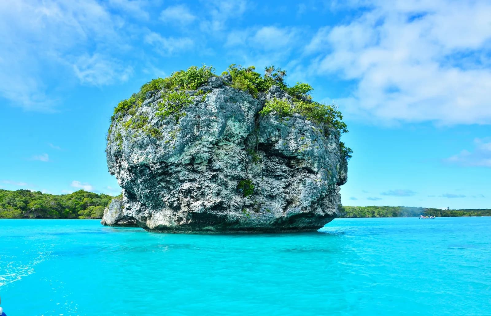 Îlot rocheux couvert de végétation dans le lagon turquoise de Nouvelle-Calédonie