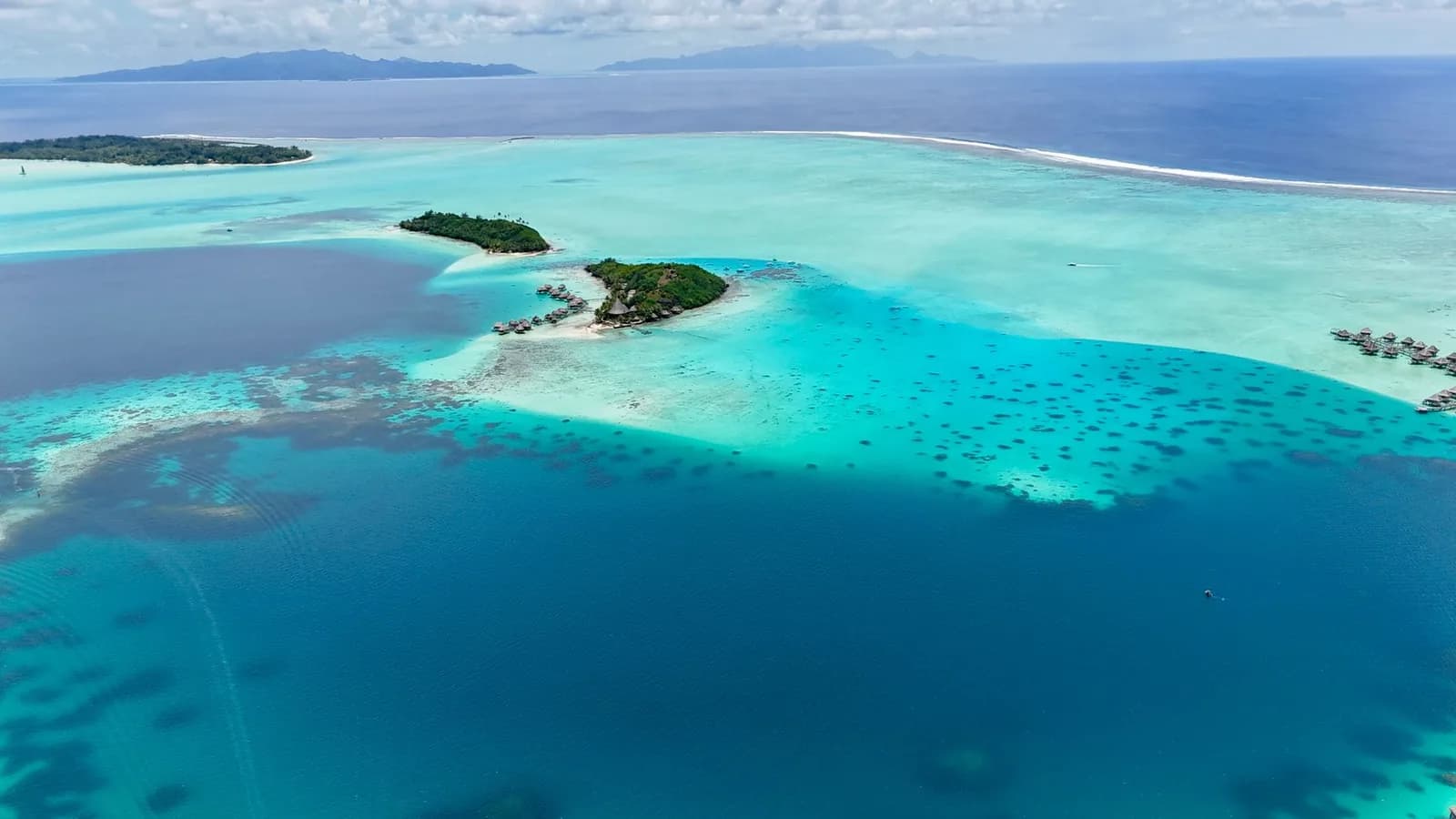 Vue aérienne d'un lagon turquoise tropical parsemé de récifs coralliens et d'îlots