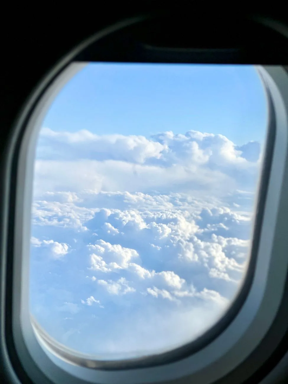 Vue à travers le hublot d'un avion sur une mer de nuages et un ciel bleu