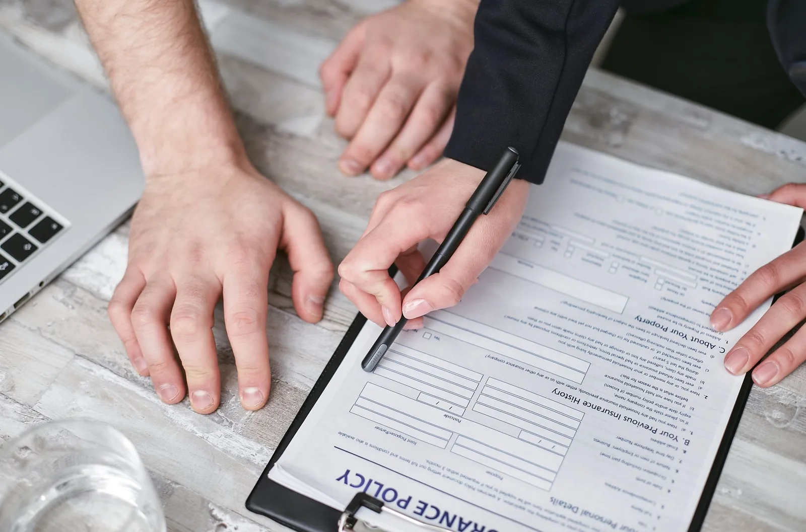 Conseiller et client remplissant ensemble un formulaire de contrat d'assurance sur un bureau