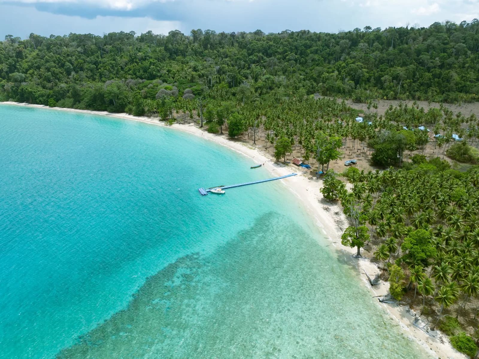 Vue aérienne d'un lagon turquoise bordé d'une plage de sable blanc et d'une forêt de cocotiers, image d'illustration évoquant les îles Loyauté (sans lien direct avec le site du drame)