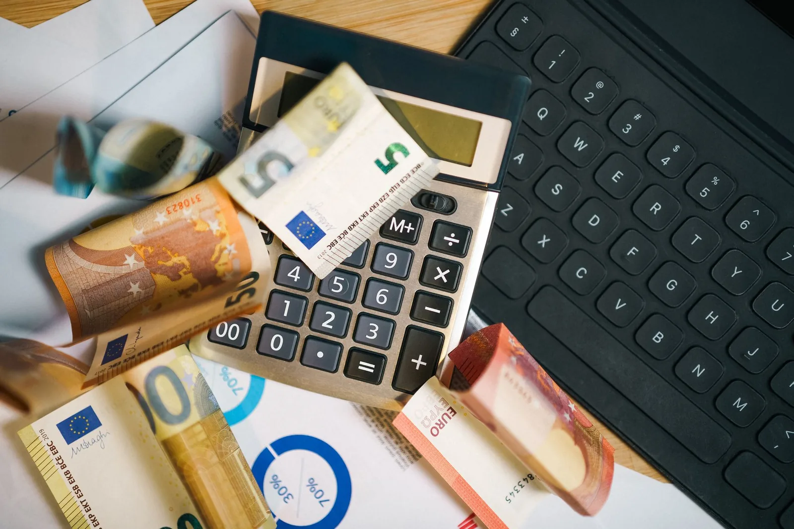 Billets en euros, calculatrice et graphiques de budget sur un bureau, illustration de la conversion entre euro et franc Pacifique