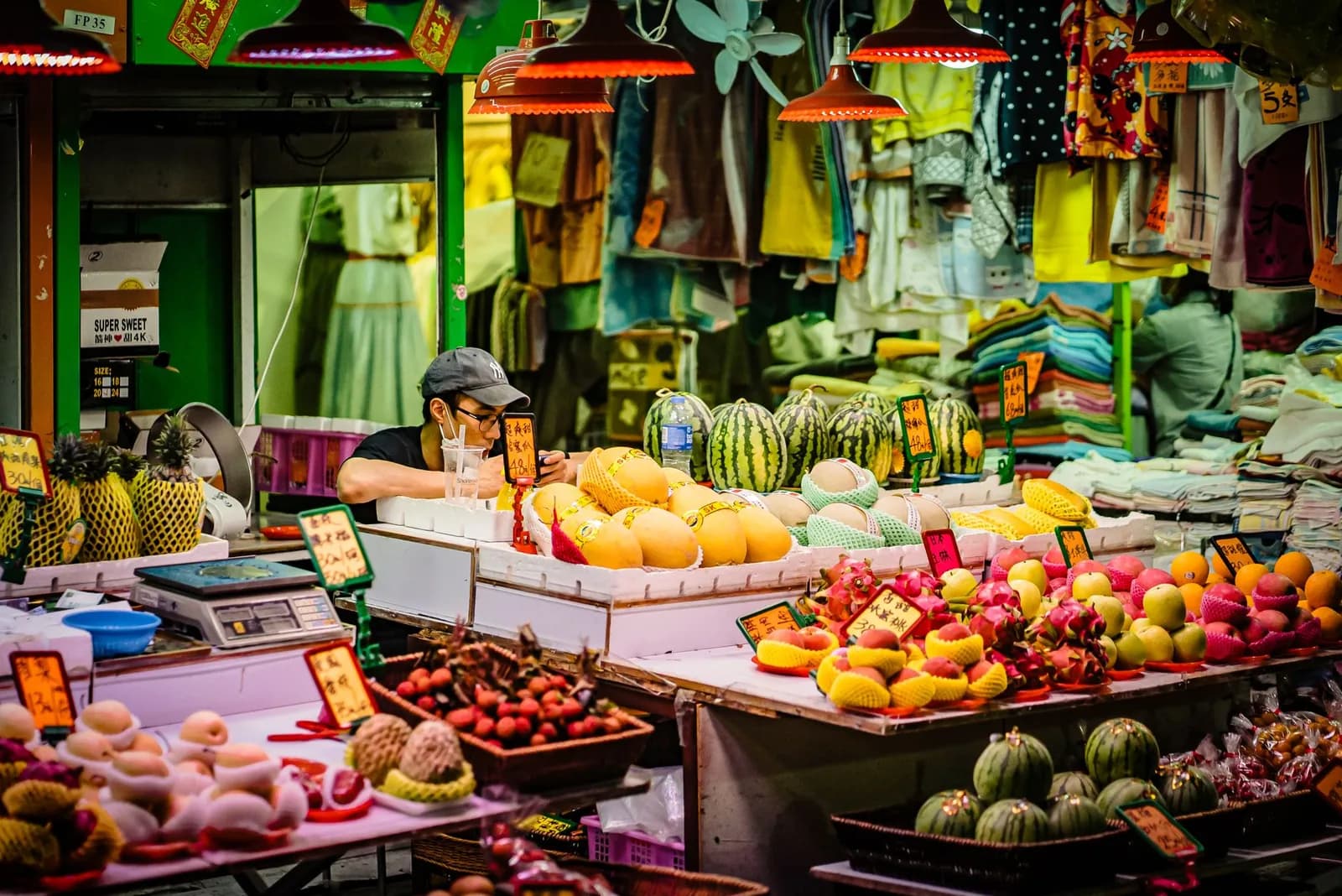 Étal de marché coloré chargé de fruits tropicaux (ananas, mangues, pastèques, fruits du dragon)