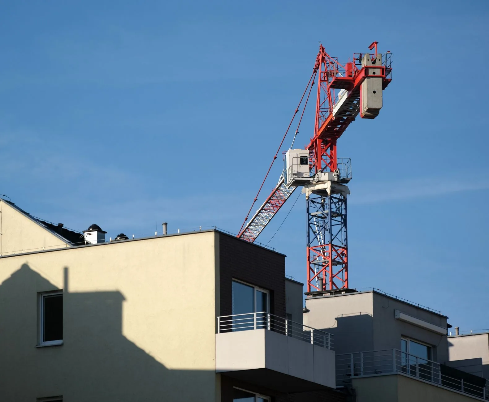 Grue de chantier rouge au-dessus d'un immeuble d'habitation en construction sous un ciel bleu