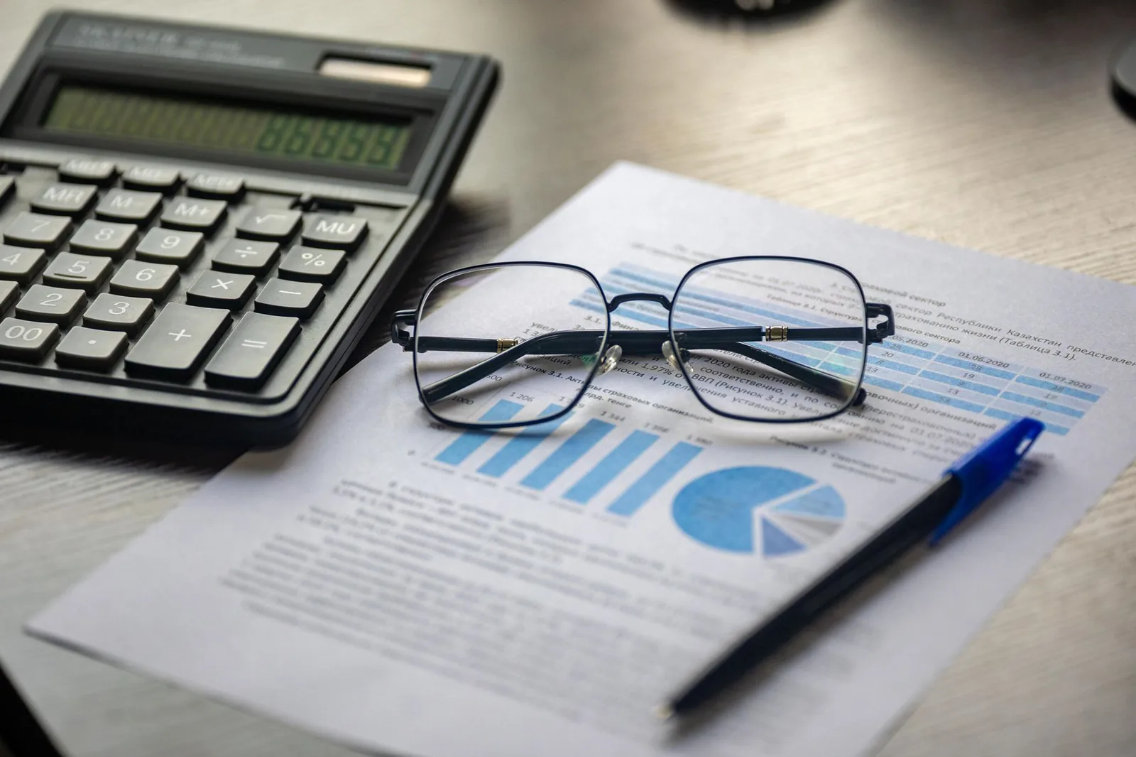 Calculatrice, lunettes et document financier avec graphiques posés sur un bureau