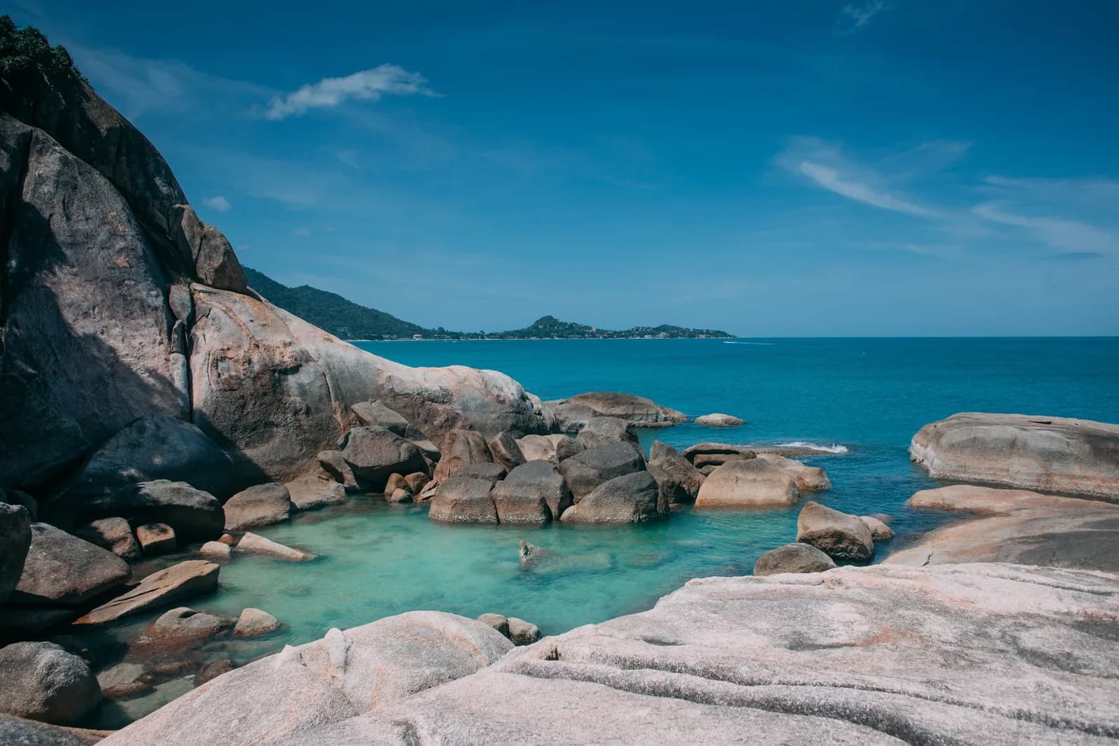 Piscine naturelle d'eau turquoise et limpide cernée de gros rochers de granit et ouverte sur l'océan