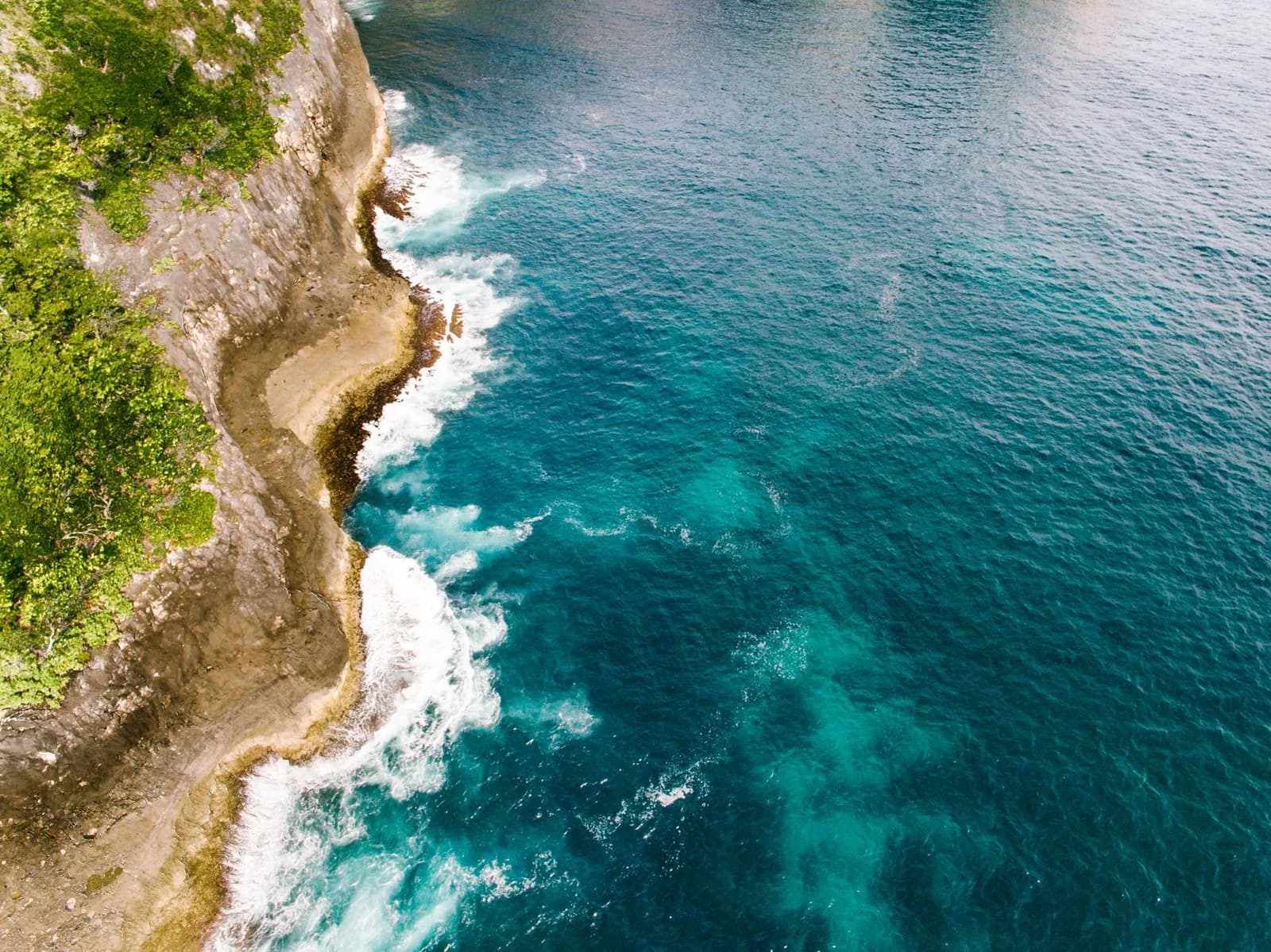 Falaise côtière plongeant dans une eau turquoise, décor évoquant les côtes escarpées des îles Loyauté