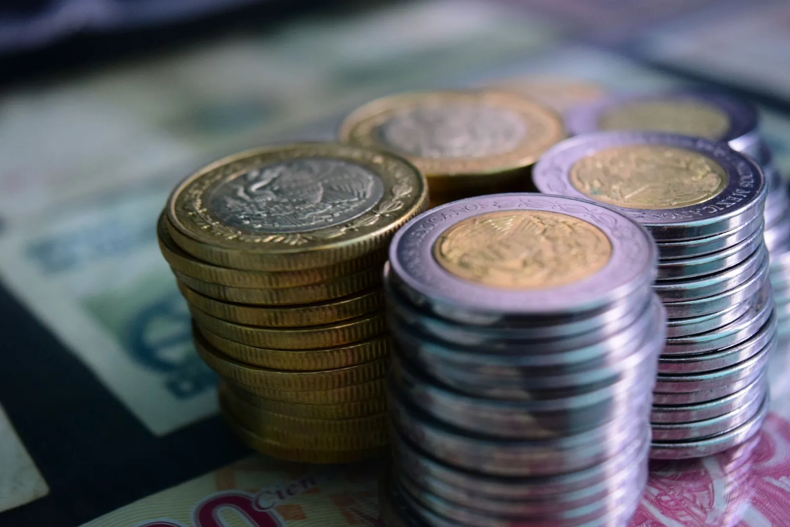 Piles de pièces de monnaie posées sur des billets de banque, symbolisant la monnaie et la fiscalité locales (image générique, non spécifique au franc Pacifique)