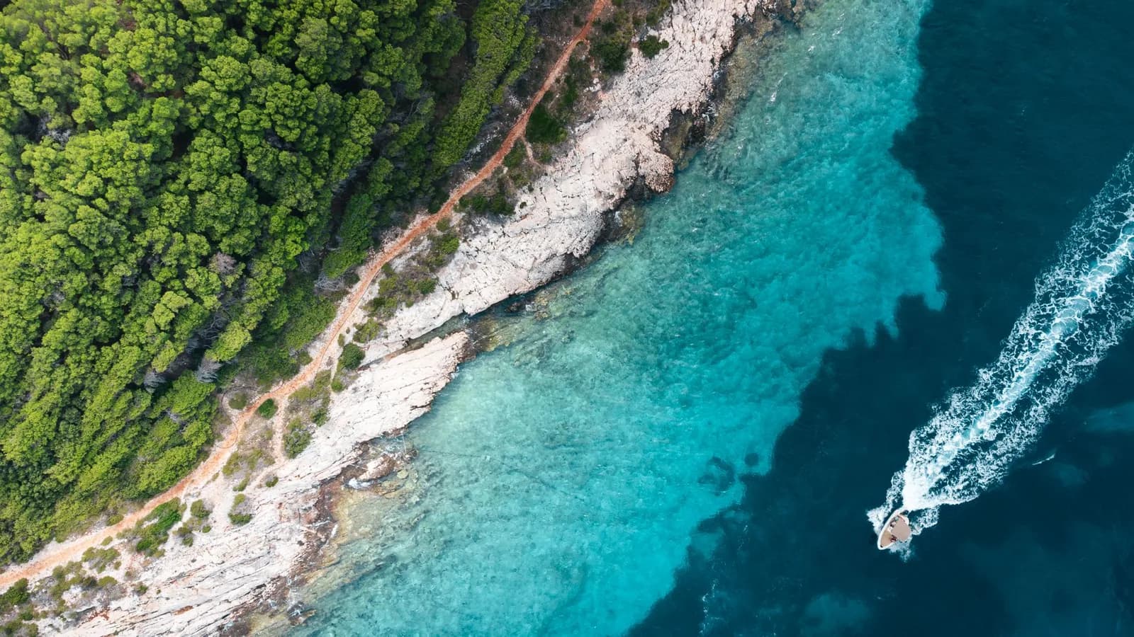Vue aérienne d'un vaste lagon turquoise parsemé de récifs coralliens, semblable aux lagons de Nouvelle-Calédonie inscrits au patrimoine mondial de l'UNESCO