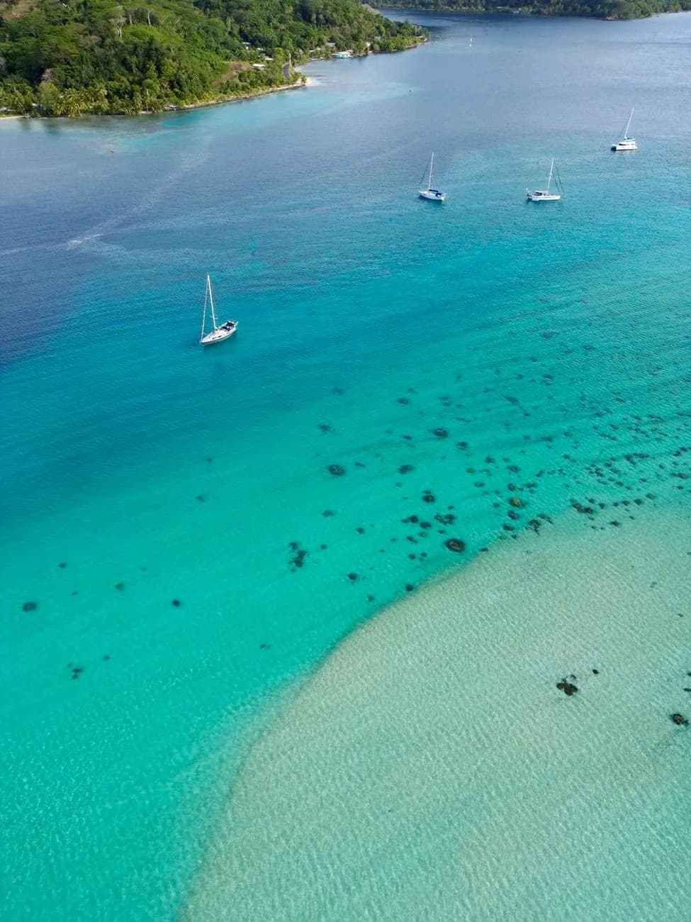 Voiliers ancrés sur un lagon turquoise vus du ciel, activités nautiques typiques du littoral de Nouméa