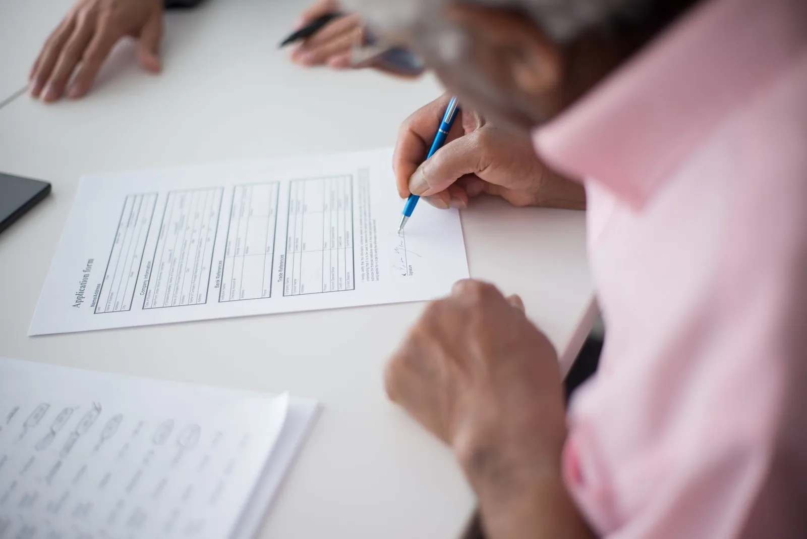 Personne remplissant et signant un formulaire de demande sur un bureau administratif