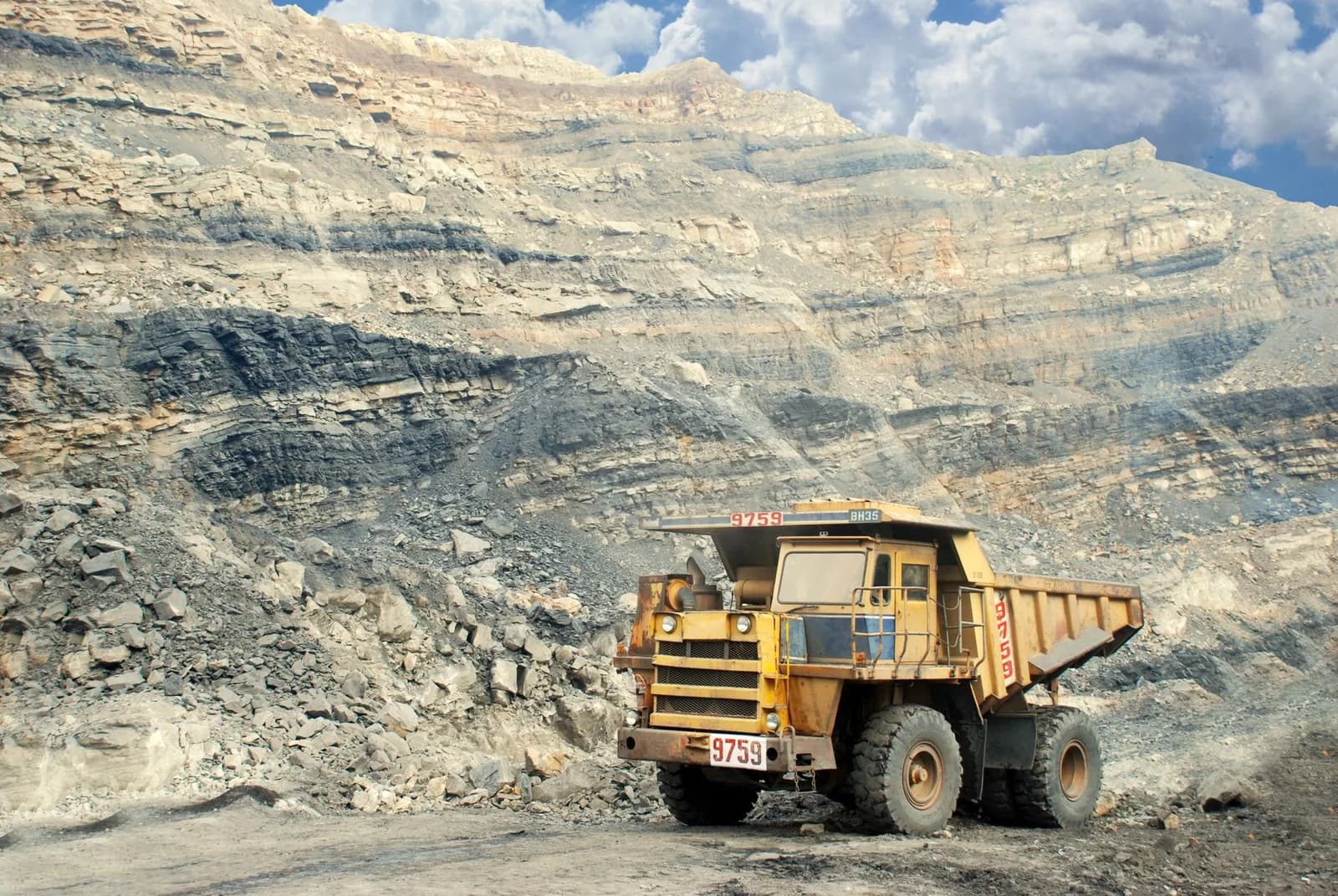 Camion-benne minier devant un front de taille rocheux dans une mine a ciel ouvert (photo d'illustration)