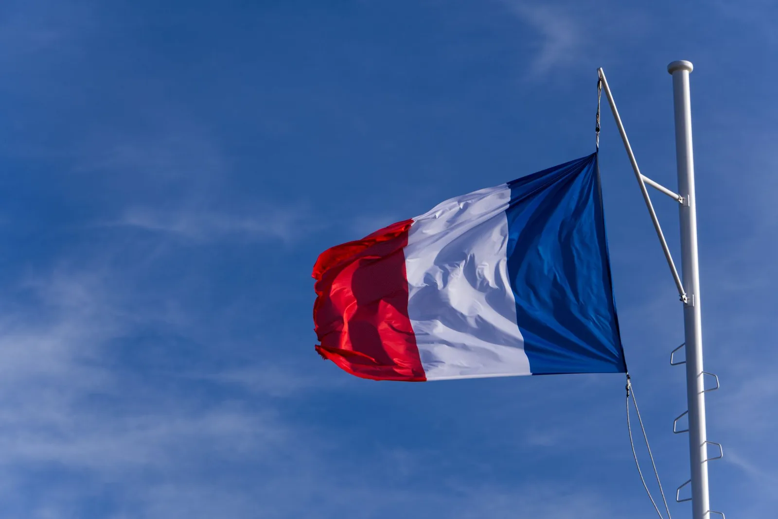 Drapeau tricolore français flottant contre un ciel bleu, évoquant le débat sur l'autodétermination (illustration)