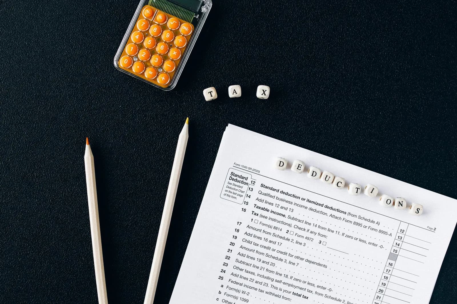 Formulaire fiscal, calculatrice et crayons posés sur un bureau sombre