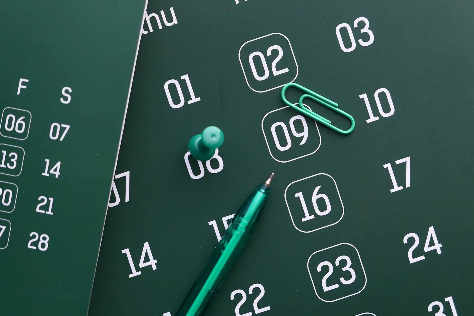 Calendrier mensuel avec plusieurs dates entourées et un stylo, illustrant le décompte des jours