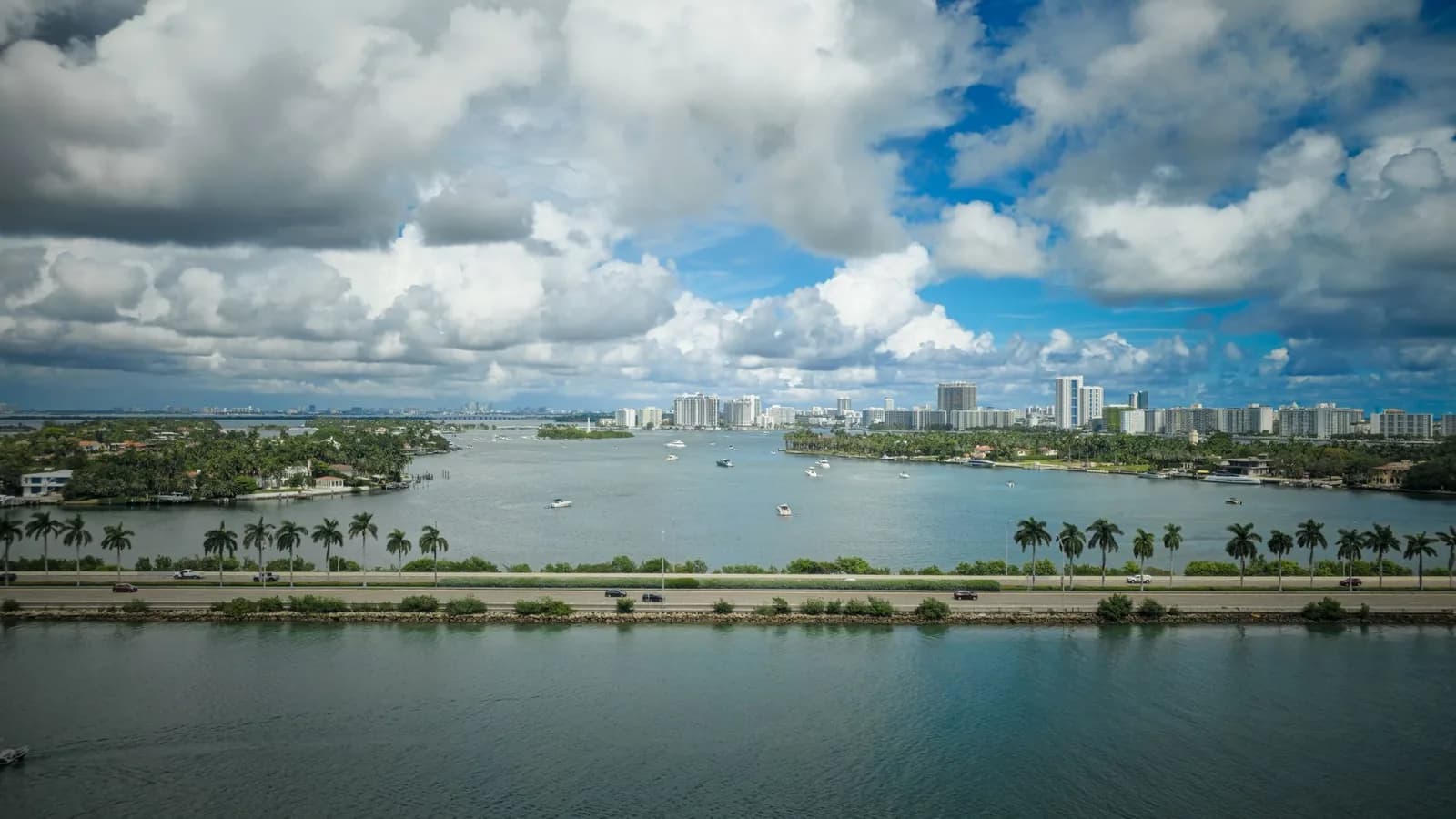 Baie résidentielle bordée de palmiers en bord de mer sous ciel tropical, évoquant un front de mer de Nouvelle-Calédonie