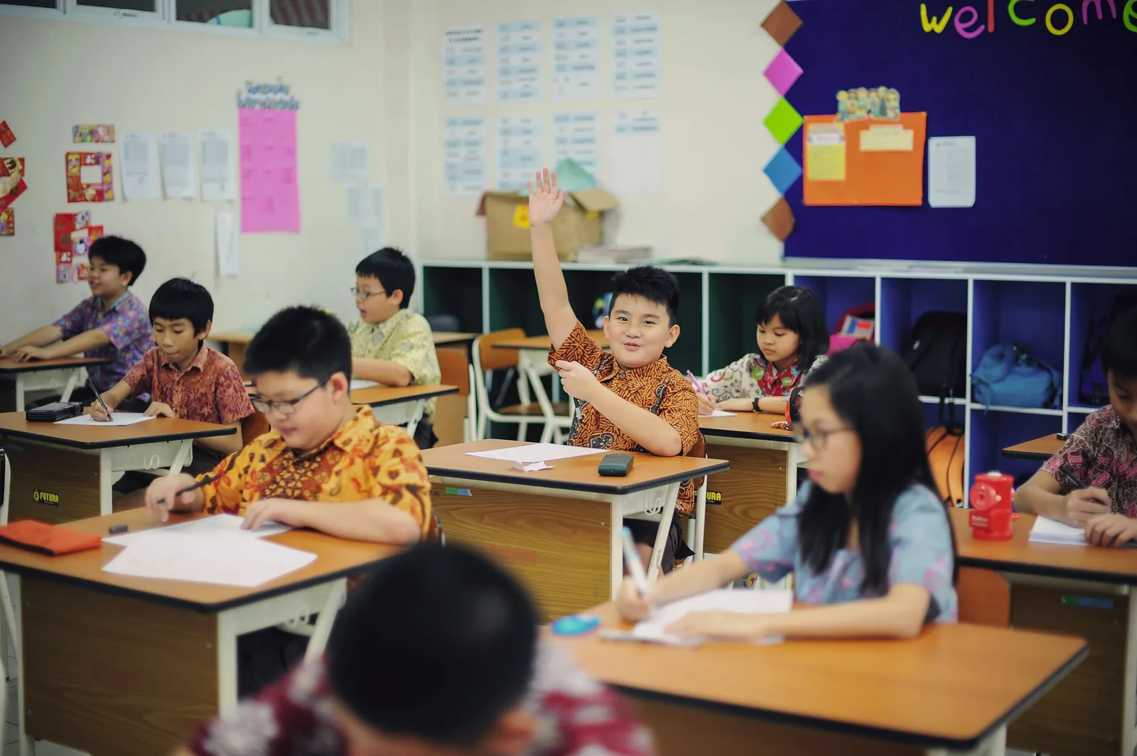 Élèves de primaire en classe, l'un levant la main, illustration générique du système scolaire (photo non localisée en Nouvelle-Calédonie)