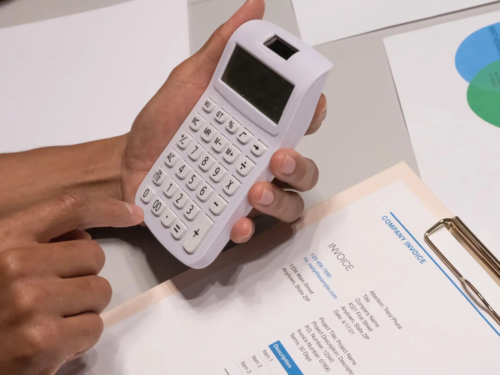 Main tenant une calculatrice au-dessus d'une facture, pour illustrer le calcul des taux de taxe
